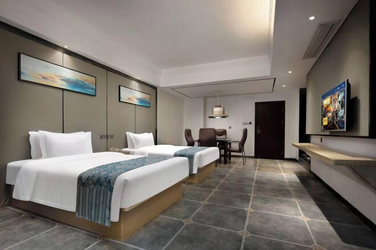 A hotel room with two beds, a desk, and a chair.
