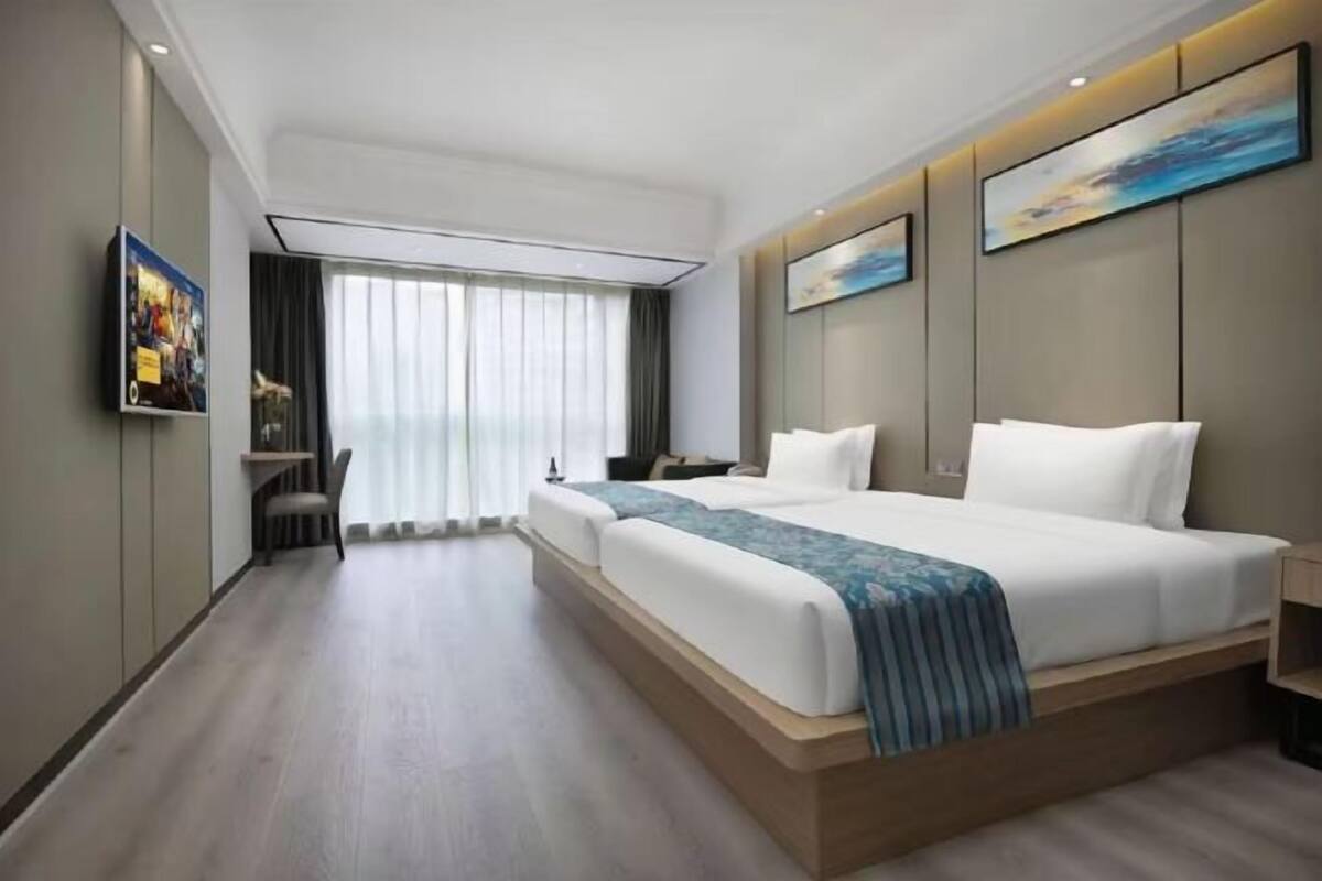 A modern hotel room with a large bed, a desk, and a chair.