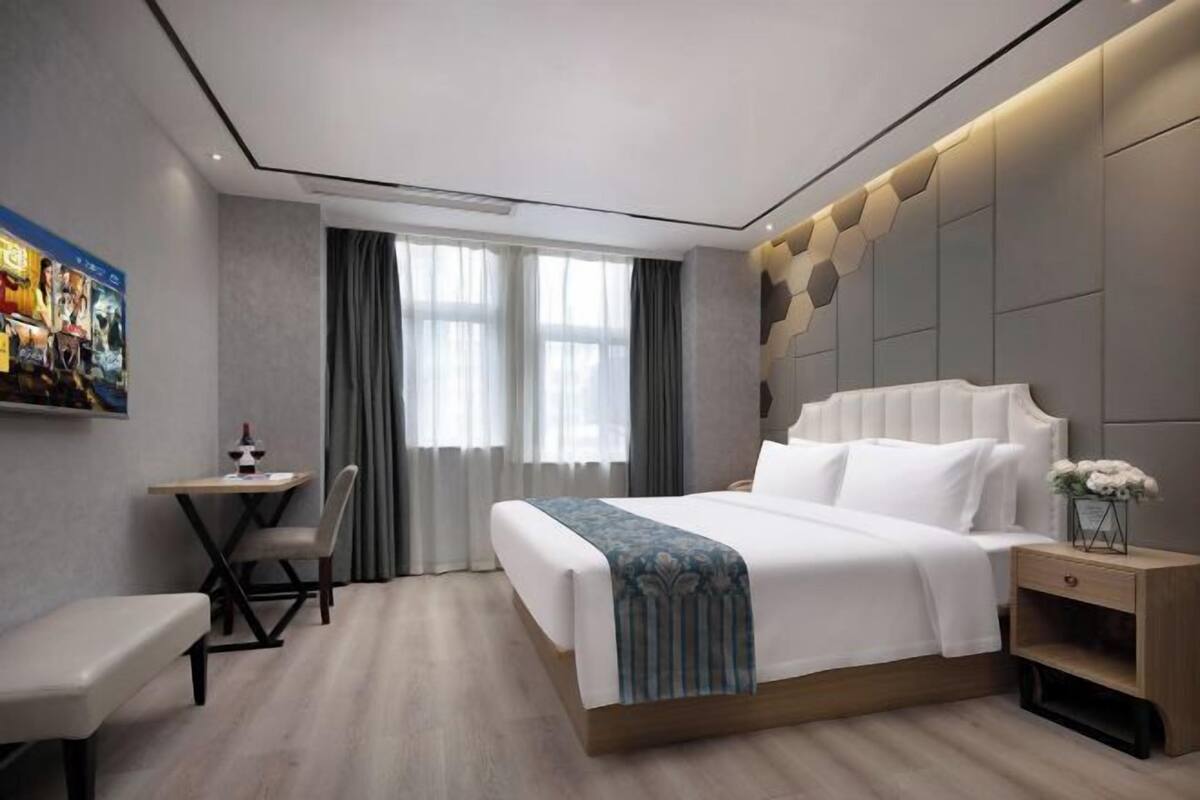 A modern hotel room with a large bed, a desk, and a chair.