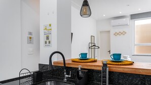 A modern kitchen with a granite countertop, a black faucet, and a built-in oven. There are two blue cups on the countertop, and a black hanging rack above the sink. - 10 Minutes From Flamengo Beach Next to the Subway Ct404 (Rio de Janeiro)