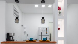 A modern kitchen with a wooden countertop, two bar stools, a coffee machine, and pendant lights. - 10 Minutes From Flamengo Beach Next to the Subway Ct404 (Rio de Janeiro)