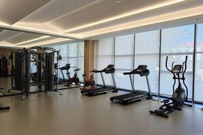 Une salle de sport équipée de tapis de course, de vélos elliptiques et de matériel de musculation.