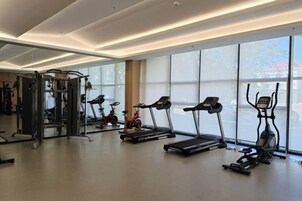 Un gimnasio con cintas de correr, elípticas y equipo de levantamiento de pesas.