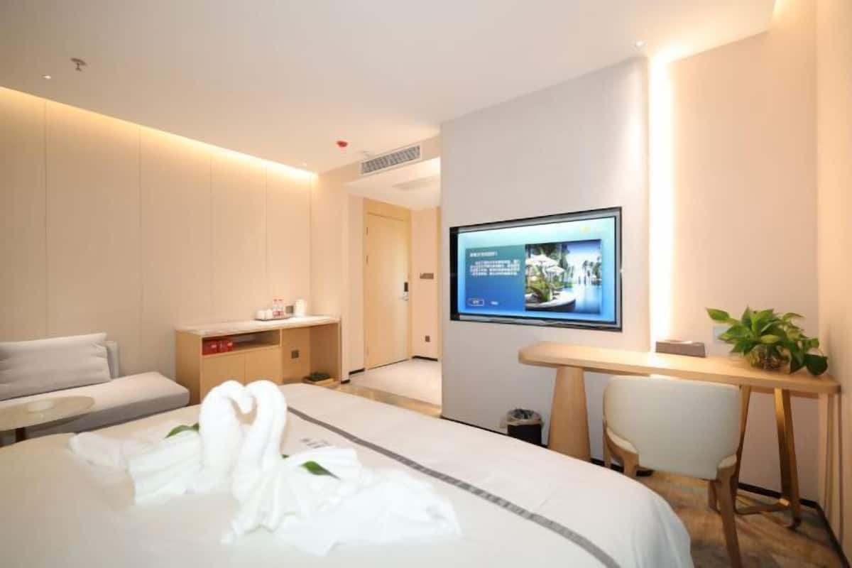Una habitación de hotel con cama, escritorio, televisor y zona de estar.