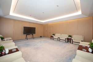 Una sala de conferencias moderna con un televisor de pantalla plana grande, asientos cómodos y piso alfombrado.