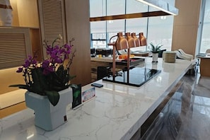 Un hall d’hôtel moderne avec un comptoir d’accueil en marbre, une plante en pot et un coin café.