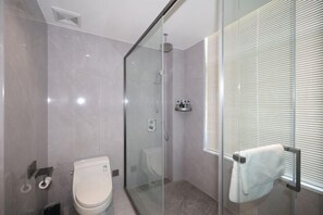 Een moderne badkamer met een douchecabine van glas, een toilet en een handdoekhouder.