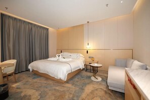 Een moderne hotelkamer met een groot bed, een klein nachtkastje, een stoel en een bank.