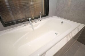 Une salle de bain moderne avec une grande baignoire blanche, une douche en verre et un sol carrelé en marbre.
