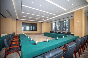 A conference room with a long table, chairs, and a large screen.