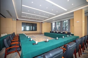 Un salón de conferencias con una mesa larga, sillas y una pantalla grande.