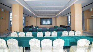 A conference room with a long table, chairs, and a large screen at the front.
