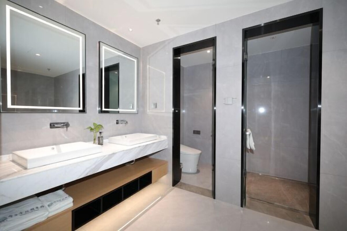 Een moderne badkamer met twee wastafels, een spiegel, een toilet en een inloopdouche.