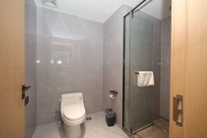 Ein modernes Badezimmer mit Toilette, einer Duschkabine aus Glas und einem Handtuchhalter.