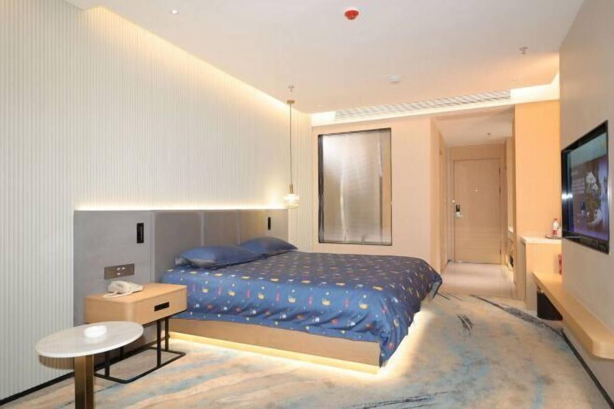 Una habitación de hotel moderna con cama, mesita de noche y televisor.
