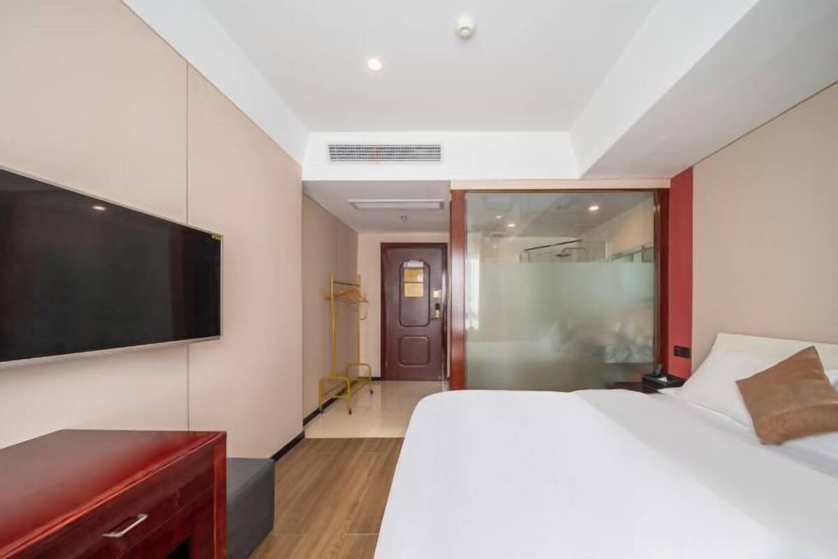 Ein Hotelzimmer mit Bett, Fernseher, Kleiderschrank und einer Tür zum Badezimmer.
