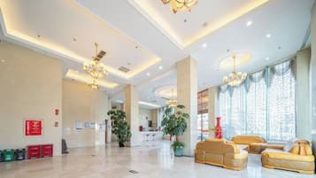 A spacious lobby with a high ceiling, chandeliers, and seating areas.
