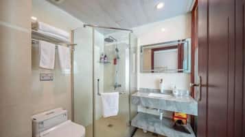 Un baño moderno con ducha de vidrio, inodoro y tocador con espejo.