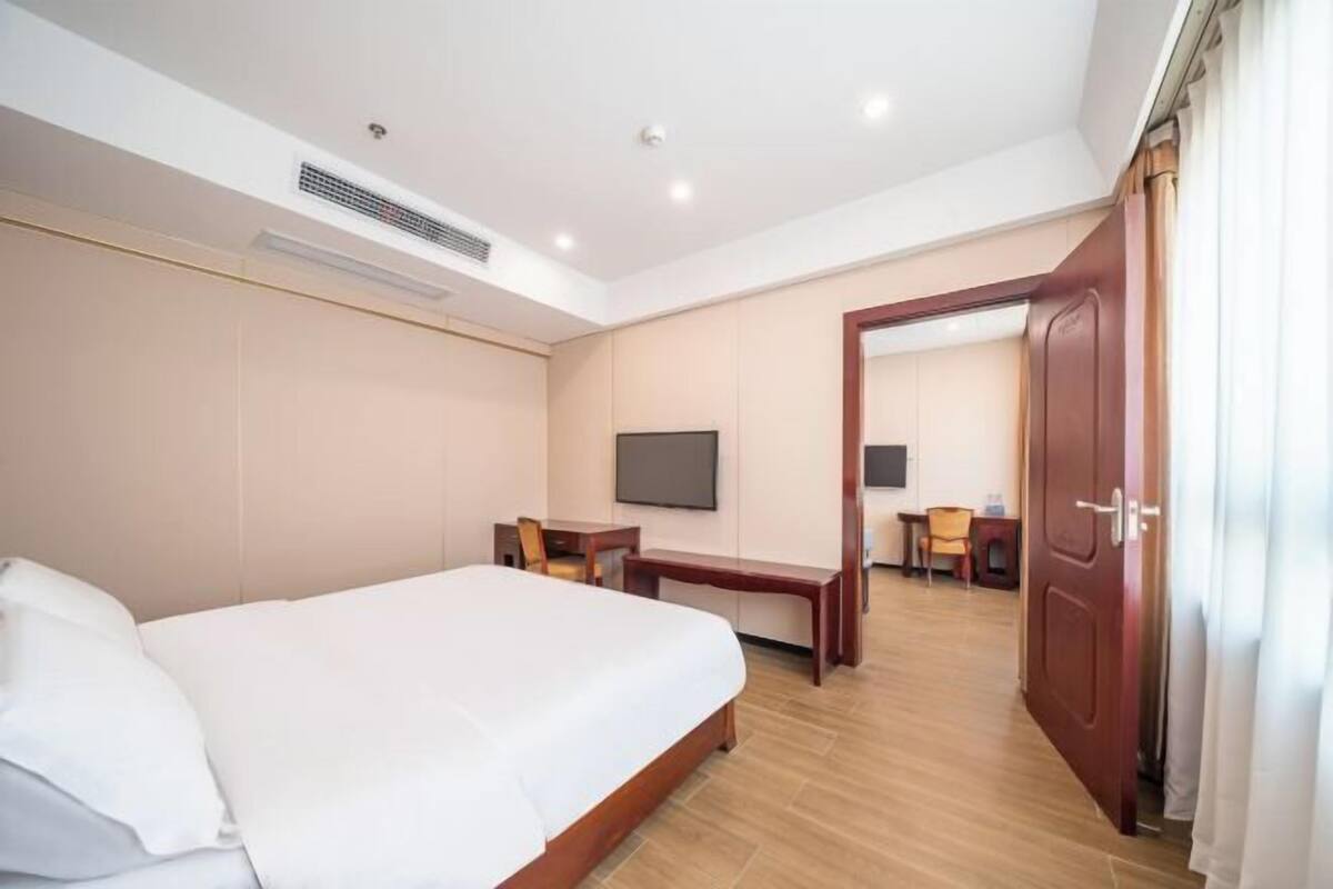 Ein Hotelzimmer mit Bett, Schreibtisch, Stuhl, Fernseher und einer Tür.