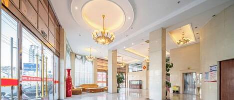 A spacious lobby with a chandelier, a reception desk, and a seating area.