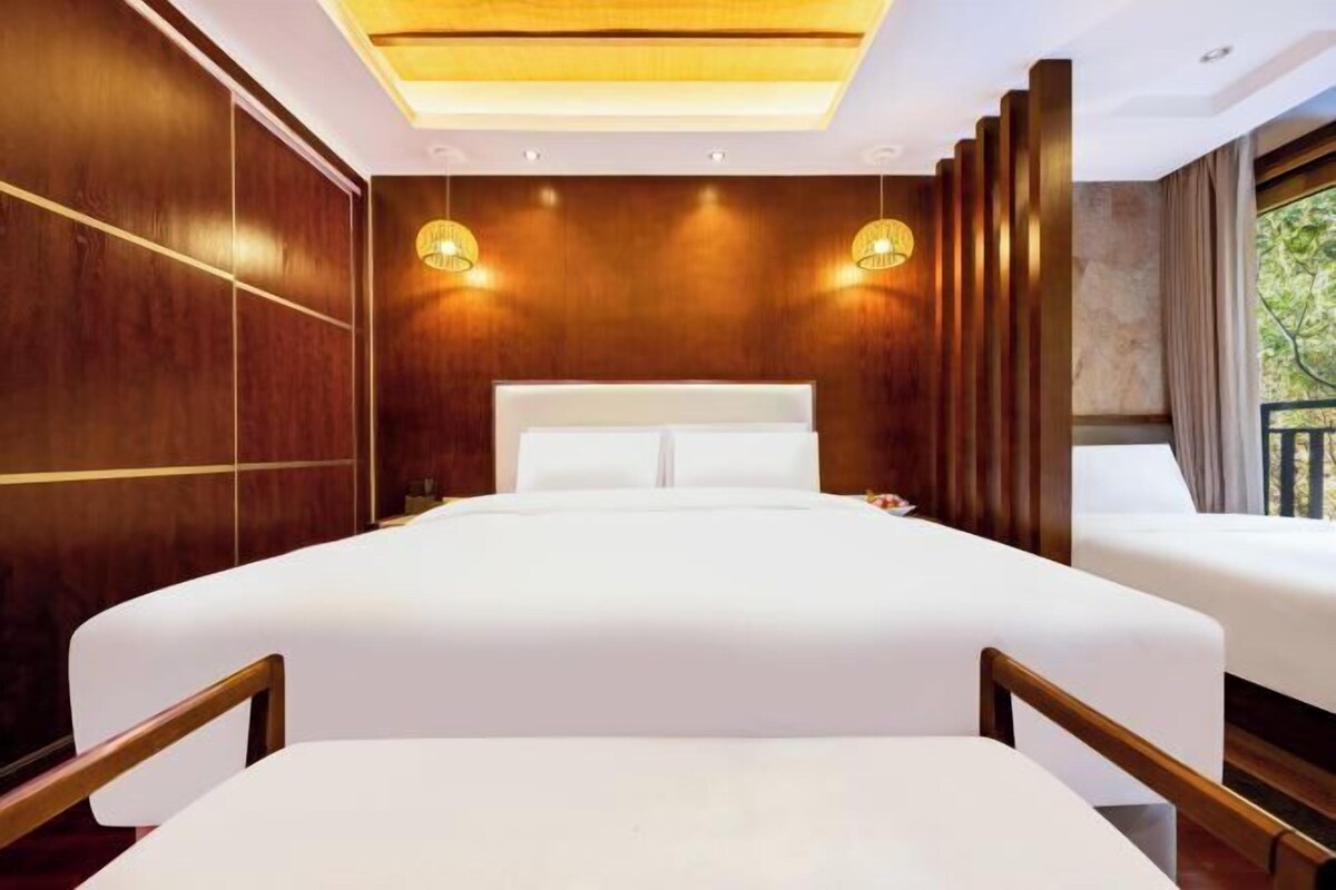 Une chambre d’hôtel moderne avec un grand lit, des panneaux de bois et deux lampes fixées au mur.