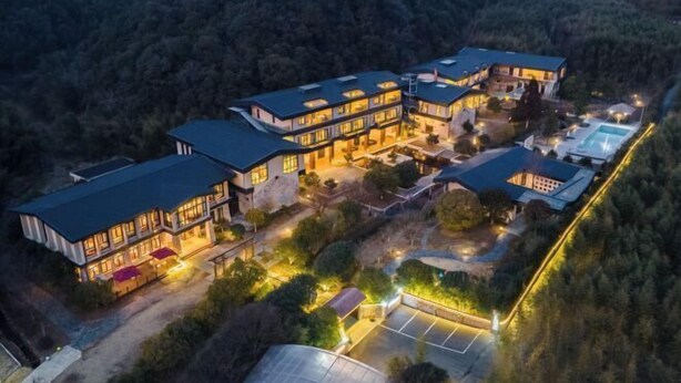 A multi-story building with a swimming pool and tennis court, surrounded by trees. - Moganshan Liangshe Health Resort Hotel (Deqing)