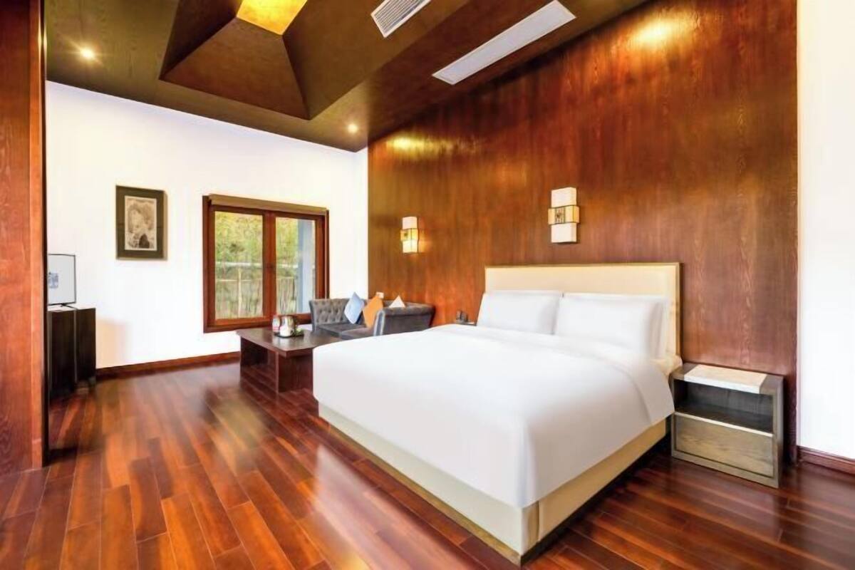 Un dormitorio moderno con una cama grande, suelo de madera, una mesita de noche y un escritorio con silla.