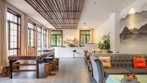 A spacious living area with a dining table, a sofa, and a kitchen in the background. - Moganshan Liangshe Health Resort Hotel (Deqing)
