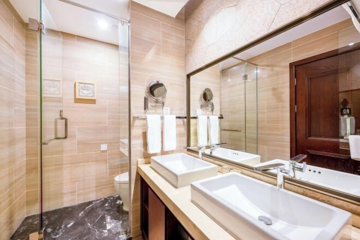 Une salle de bain moderne avec deux lavabos, un grand miroir et une douche à l’italienne.