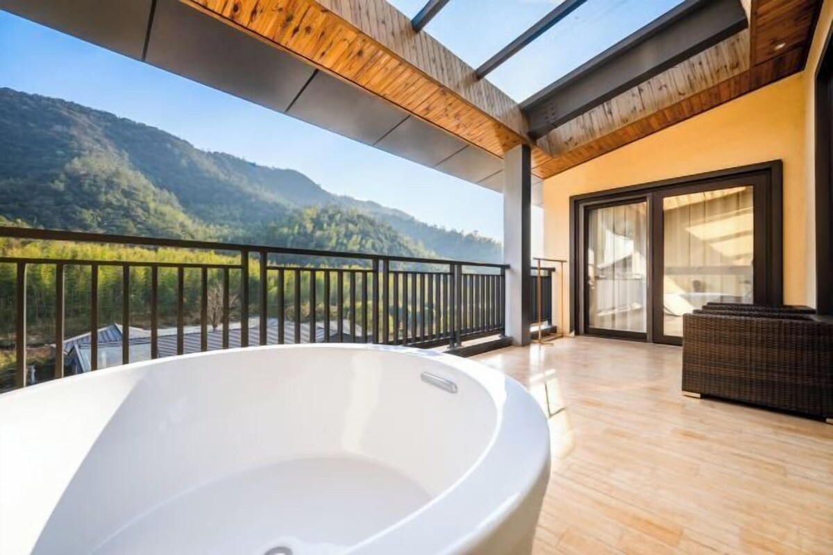 Un balcon moderne doté d’un jacuzzi, d’un plafond en bois et offrant une vue sur les montagnes.