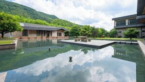 A serene hotel courtyard with a reflective pool, a stone building, and a modern structure. - Moganshan Liangshe Health Resort Hotel (Deqing)