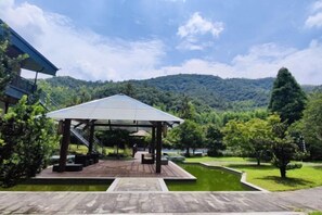 Un espace extérieur abrité doté d’une terrasse en bois, de sièges et offrant une vue sur un lac et des collines boisées.