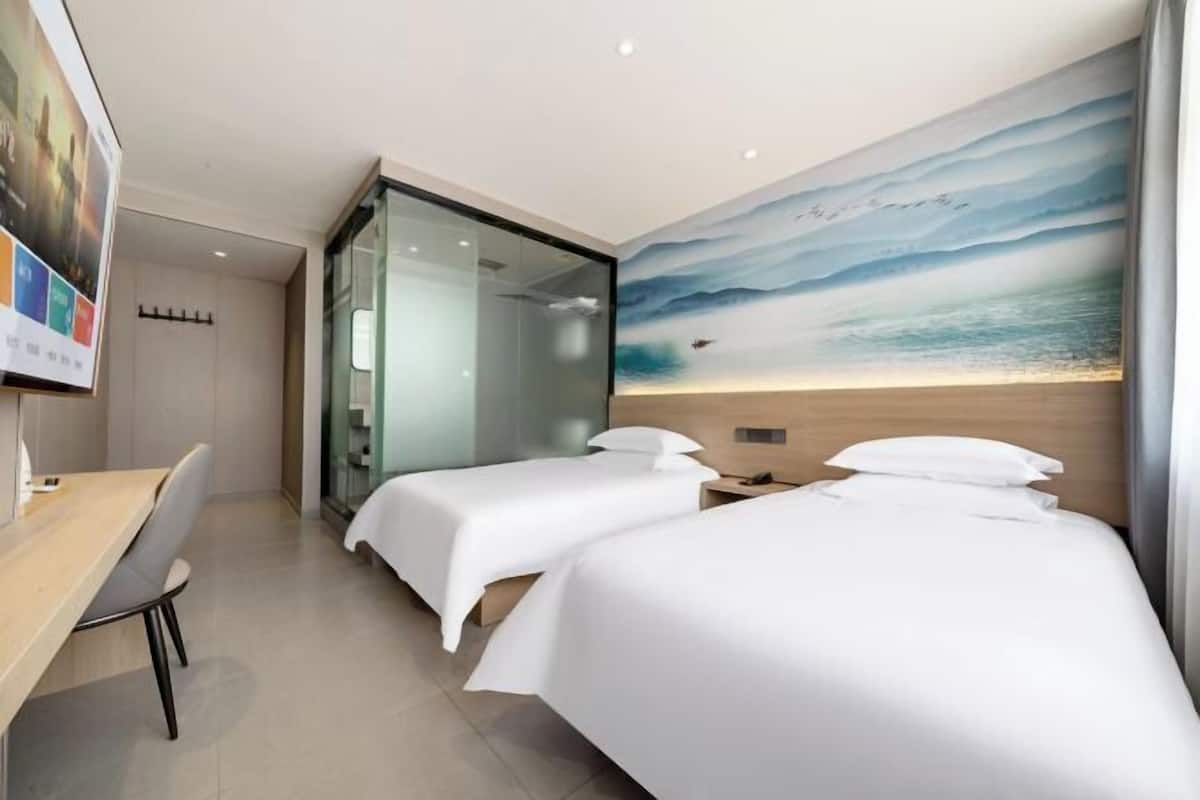 Habitación de hotel con dos camas, un escritorio y un separador de vidrio.