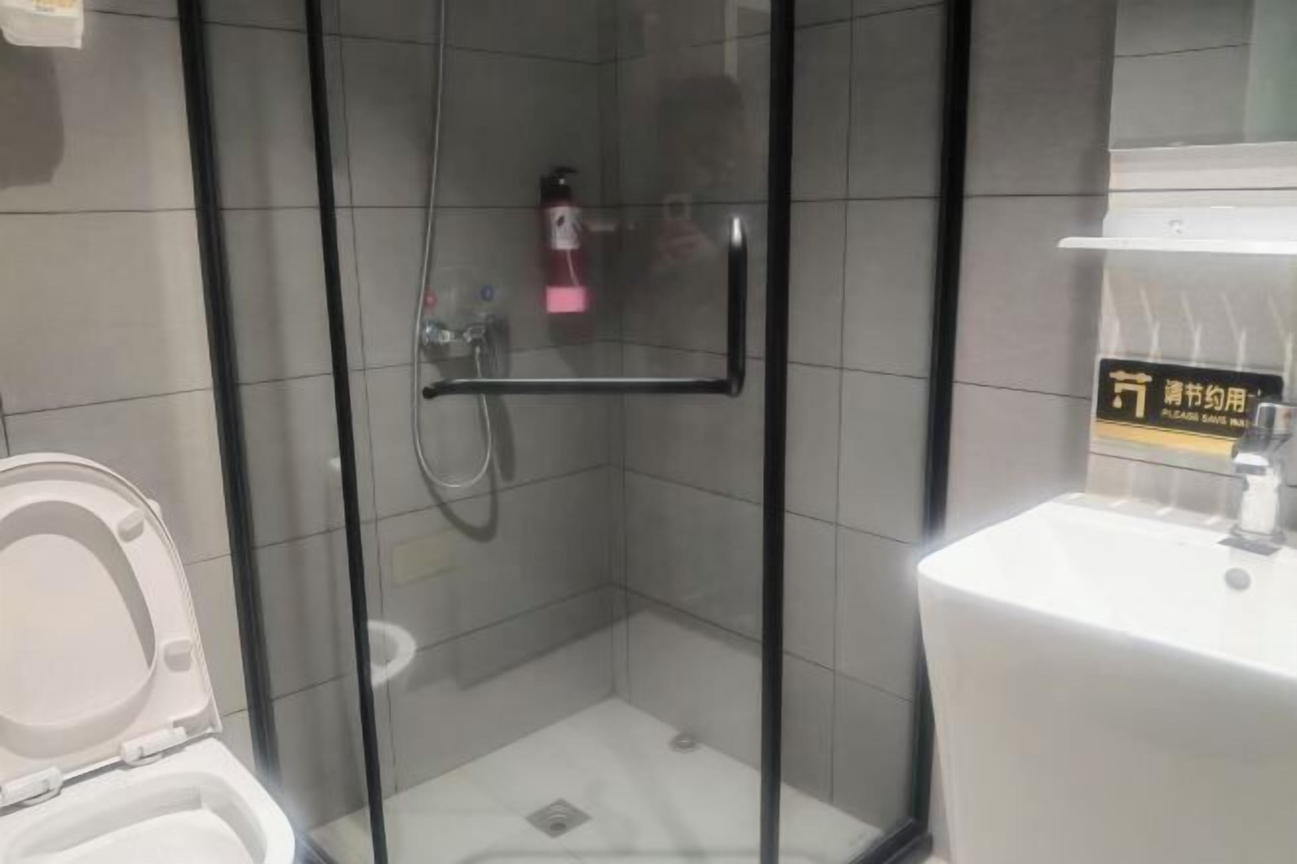 Een moderne badkamer met een douchecabine van glas, een witte wastafel en een toilet.