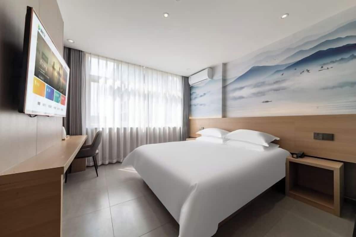Una habitación de hotel moderna con una cama grande, un escritorio y un cuadro en la pared.
