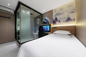 A hotel room with a bed, a desk with a computer, a wall-mounted TV, and a sliding glass door leading to a balcony. - Sangpin E-sports Hotel (Wenzhou Guoxi Branch) (Wenzhou)