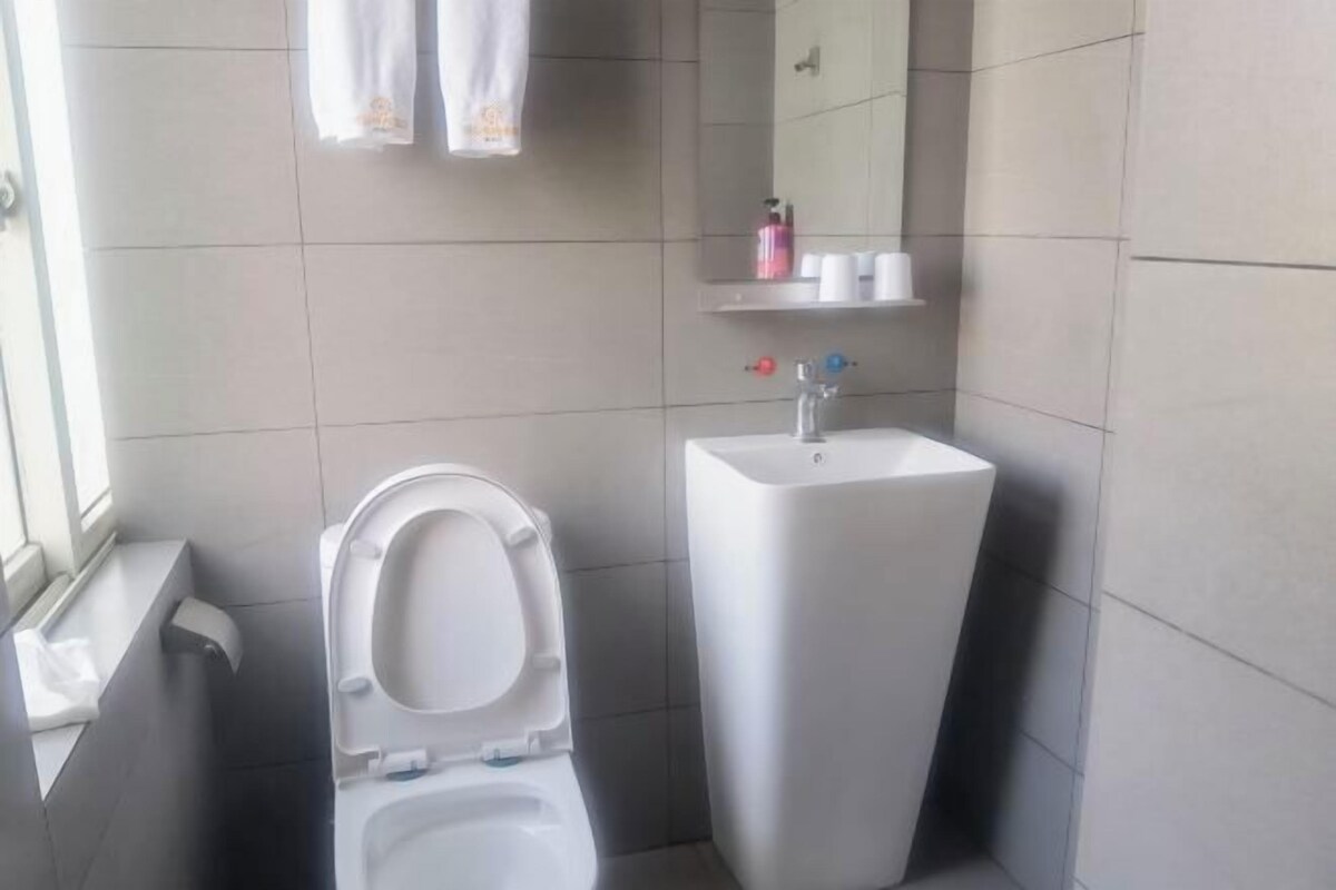 A bathroom with a toilet, a sink, and a mirror. There are towels hanging on the wall and toiletries on the sink.