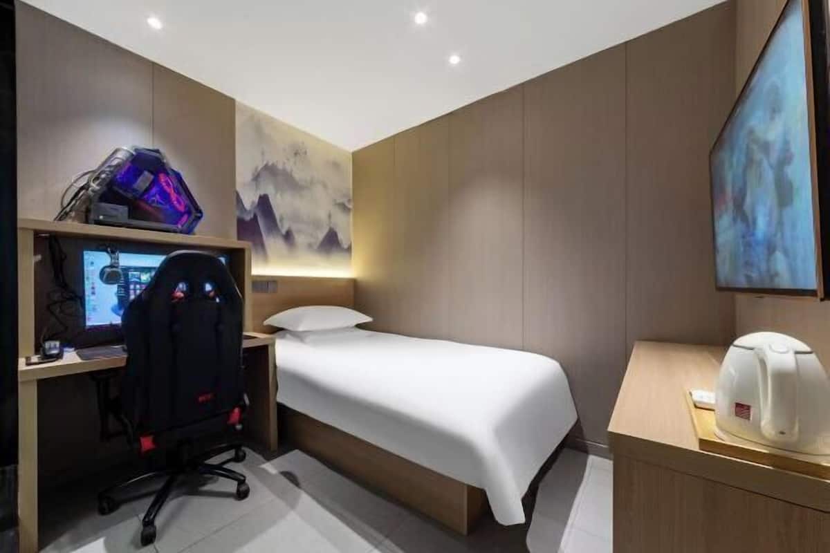 Una habitación de hotel con cama, escritorio, silla y televisor.