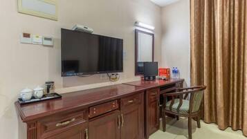 Habitación de hotel con un escritorio de madera, un televisor, un espejo y una silla.