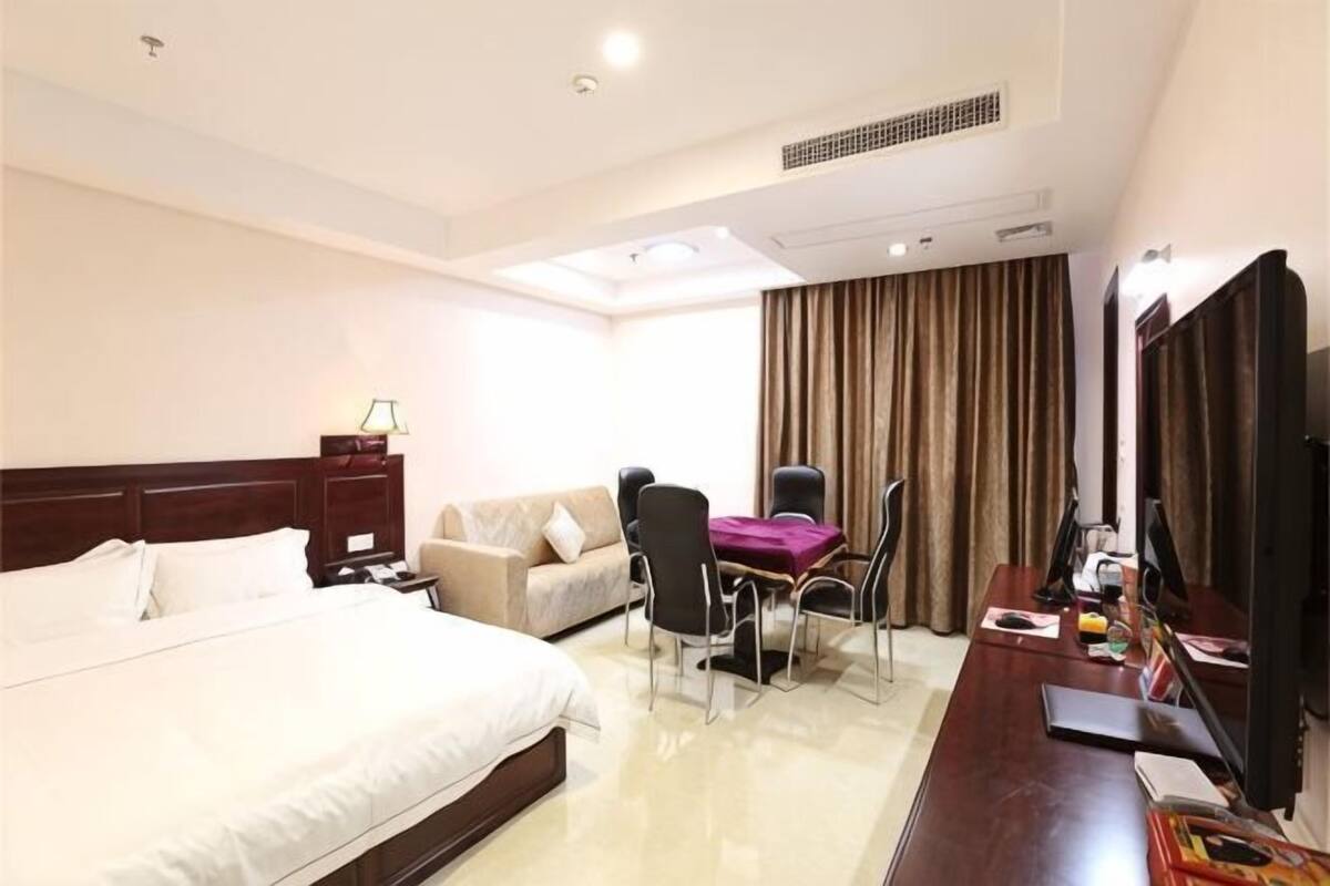 A hotel room with a bed, a desk with a chair, a sofa, and a TV.