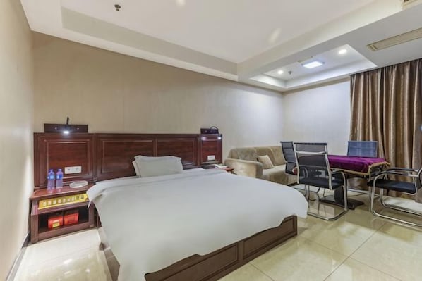 A hotel room with a large bed, bedside tables, a desk with a chair, and a window with curtains.