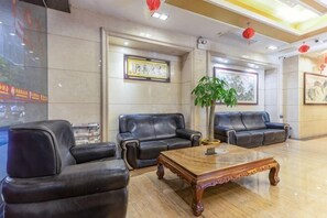 A lobby with leather sofas, a wooden coffee table, and framed artwork on the walls.