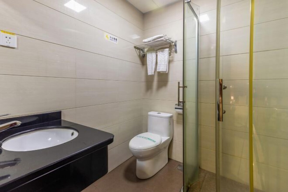 A bathroom with a black sink, white toilet, and a glass shower enclosure.