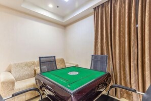 A room with a pool table, two chairs, a sofa, and a curtain.