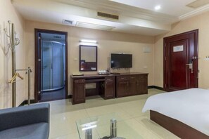 A hotel room with a bed, a desk with a TV, a mirror, a wardrobe, and a bathroom with a shower. - Hong Xin Business Hotel (Guangzhou)