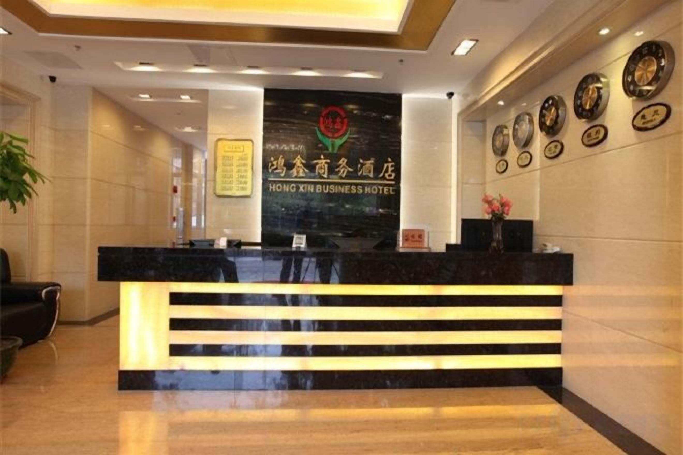A hotel reception desk with a modern design, a reception area, and a wall with framed items.