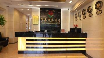 A hotel reception desk with a modern design, a reception area, and a wall with framed items.