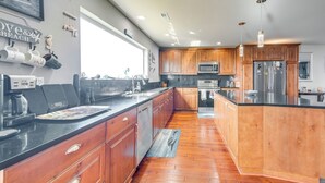 A modern kitchen with wooden cabinets, stainless steel appliances, and a large island. - Ocean Shores Retreat w/ Fire Pit - Walk to Beach! (Ocean Shores)