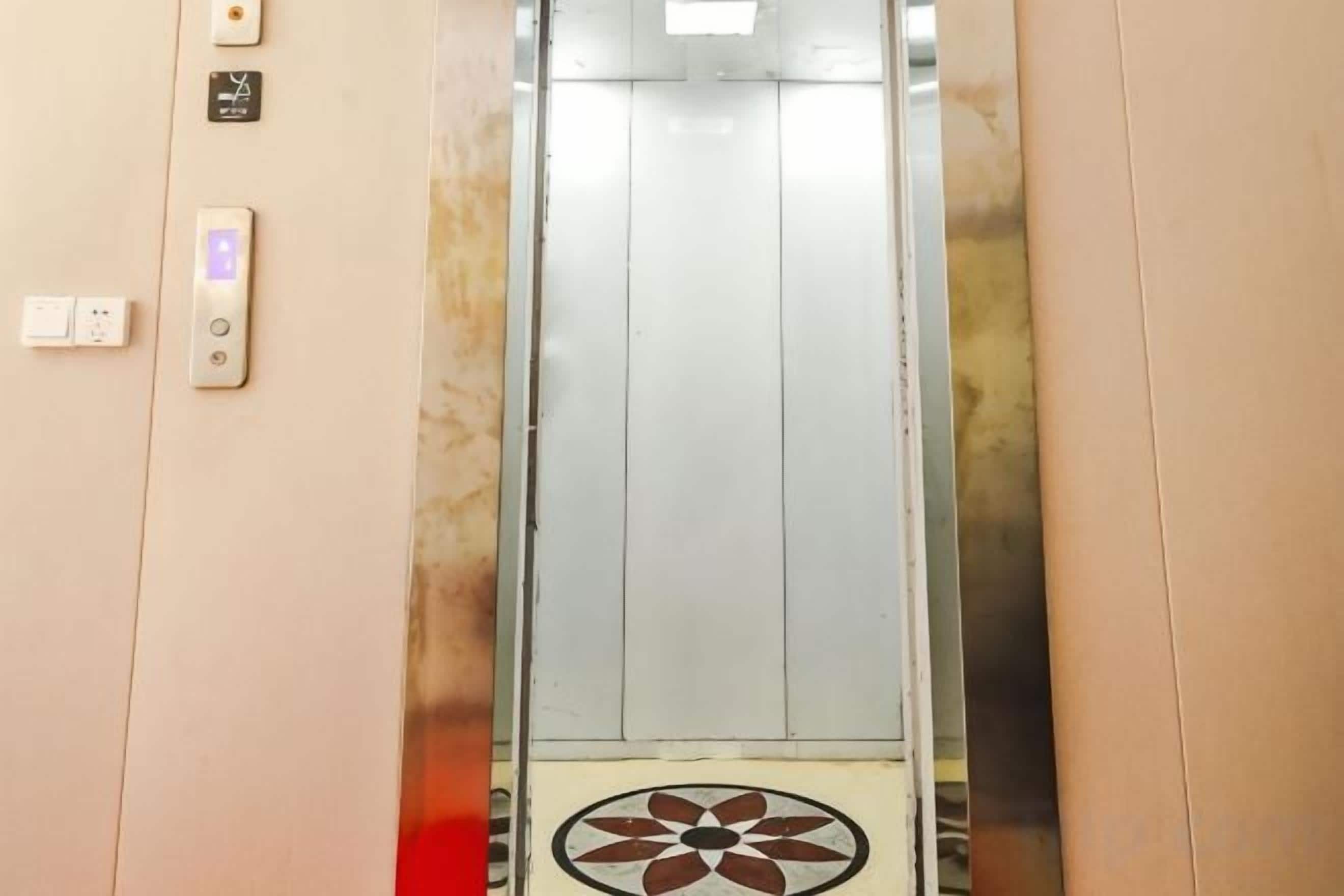 Un ascensor con interior metálico y suelo estampado.