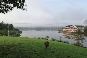 A serene lake with a building reflecting on the water, surrounded by greenery. - Starlight Hotel(Jinggangshan Railway Station Store) (Jinggangshan City)